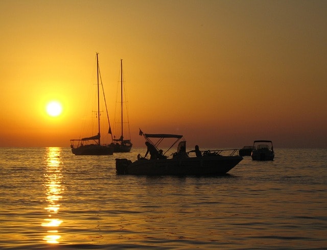 Few boats sailing in the sunset